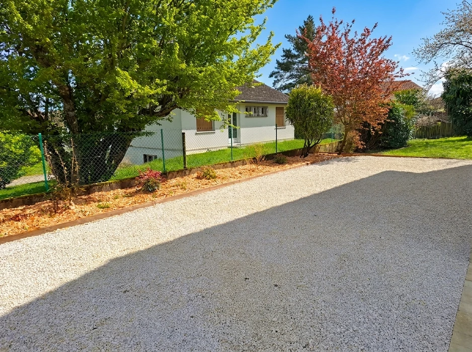 Allée de maison en gravillon blanc compacté, bordée d'une lisière en bois séparant une massif paillé de copeaux