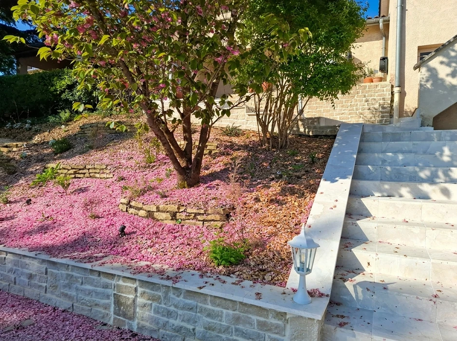 Jardin en pente aménagé avec murets en pierre sèche calcaire, escalier extérieur en marbre blanc poli
