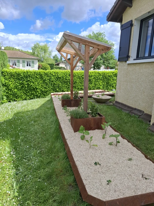 Jardin partagé urbain ensoleillé avec potager surélevé en acier galvanisé anthracite à parois ondulées, pergola en bois douglas, carrés potagers en béton préfabriqué, abri de jardin en métal, arrosoir, récupérateur d'eau