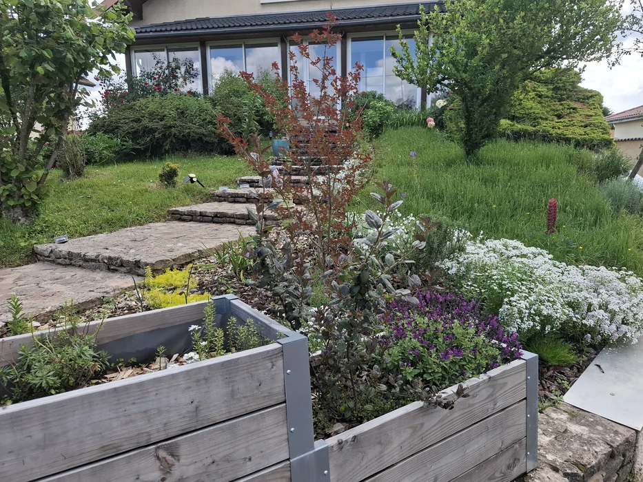 Jardin extérieur ombragé avec massif délimité par une traverse en bois vieilli