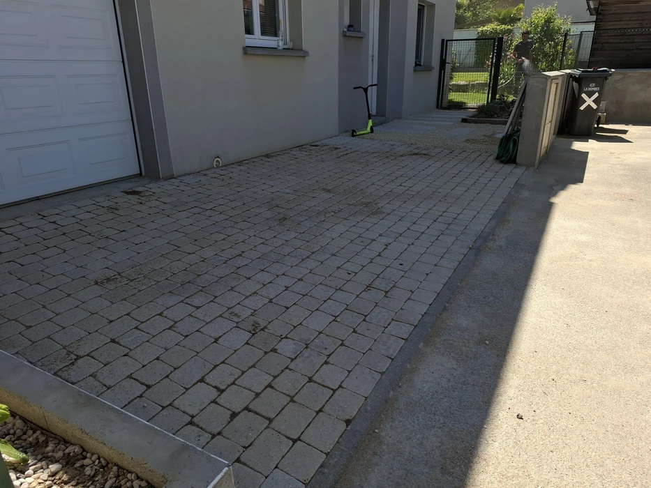 Clôture en bois horizontale récemment installée, séparant une allée goudronnée d'une propriété voisine